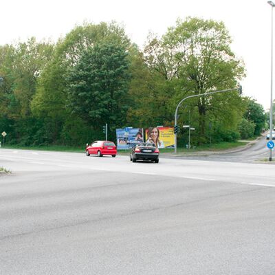 Das Bild zeigt eine Kreuzung, im Hintergrund ist ein großes Wahlplakat zu sehen.