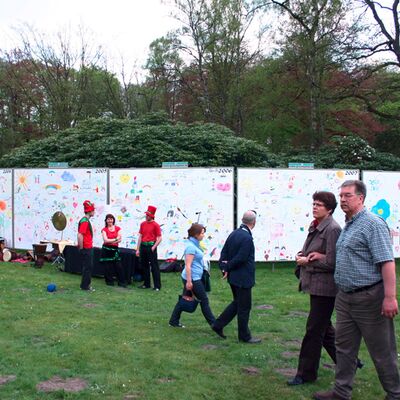 Eine Ausstellung auf einer grünen Wiese mit zahlreichen großen Plakaten, die von Kindern gemalt wurden.